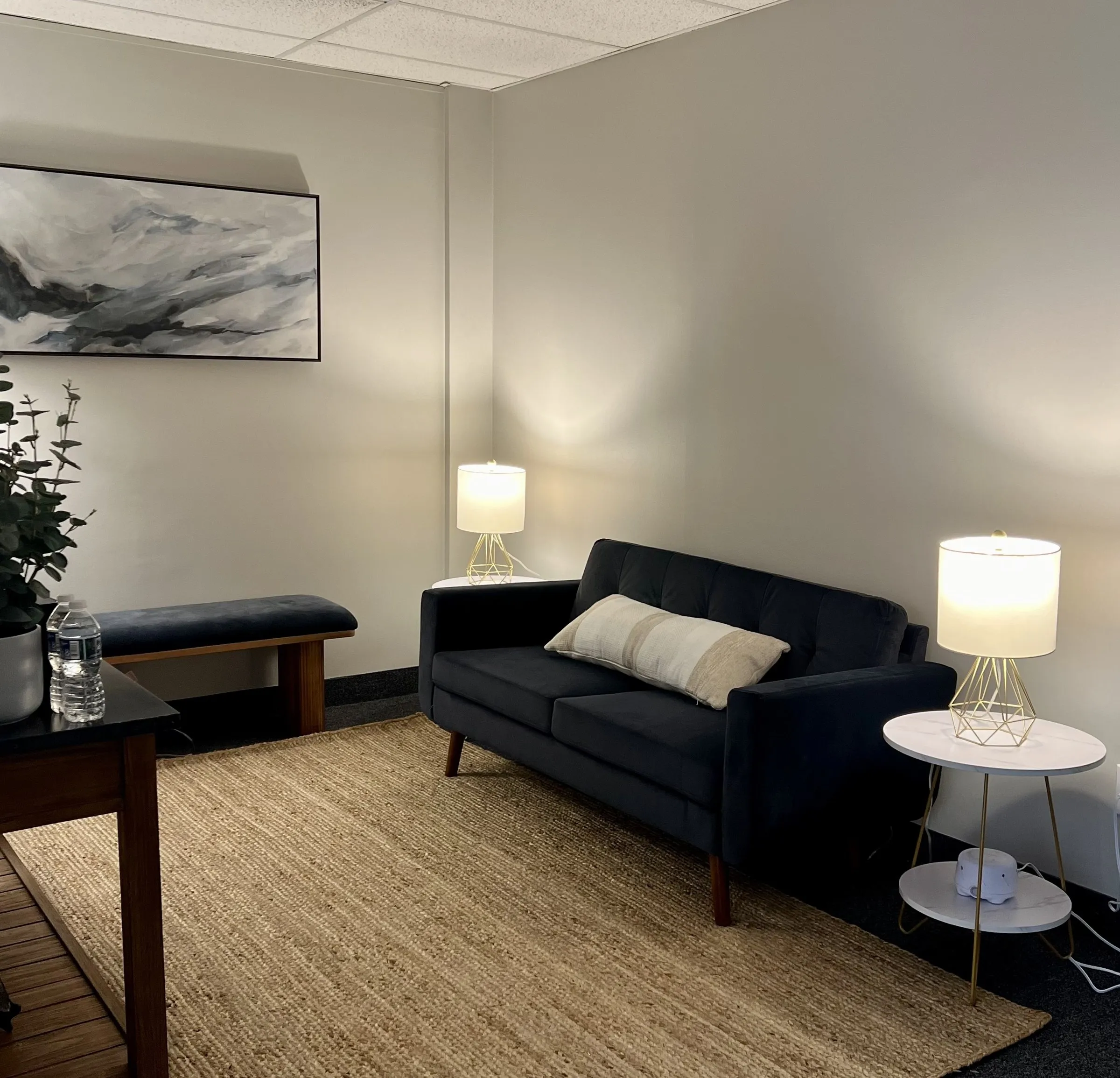 A velvet loveseat between two glowing lamps on a woven rug